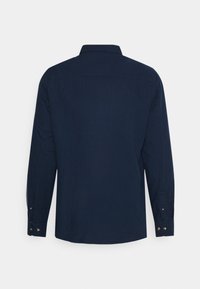 Chemise navy à manches longues avec un col classique, des poignets boutons et un tissu texturé. La vue arrière présente un design lisse et épuré.