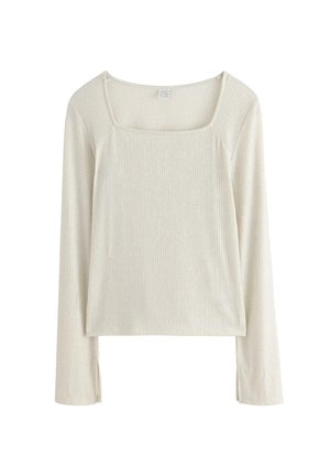 Långärmad topp i ljusbeige ribbad tyg med fyrkantig halsringning och sidoklipp för extra detalj. Slät textur, avslappnad design.