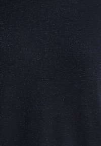 Pull en laine bleu marine foncé avec une surface texturée. Présente de subtils éclats métalliques, créant un effet scintillant. Tissu tricoté lisse.