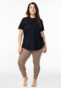 T-shirt in cotone nero con maniche corte abbinato a leggings beige. Il t-shirt è morbido, mentre i leggings sono aderenti.