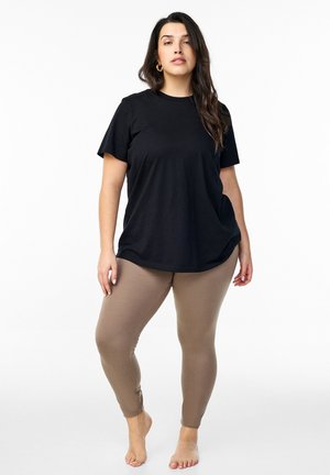 T-shirt in cotone nero con maniche corte abbinato a leggings beige. Il t-shirt è morbido, mentre i leggings sono aderenti.