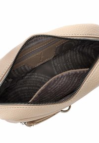 Borsa a mano in pelle beige con superficie texturizzata. L'interno presenta un rivestimento scuro con testo ripetuto e una tasca con zip. Fibbia della cerniera in argento.