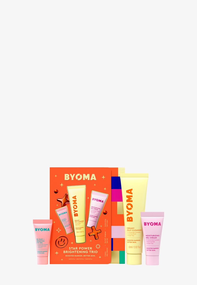 Le set BYOMA Star Power Brightening Trio se compose de trois tubes : un nettoyant jaune, une gel-crème rose et un tube rose plus grand, le tout sur un fond orange.