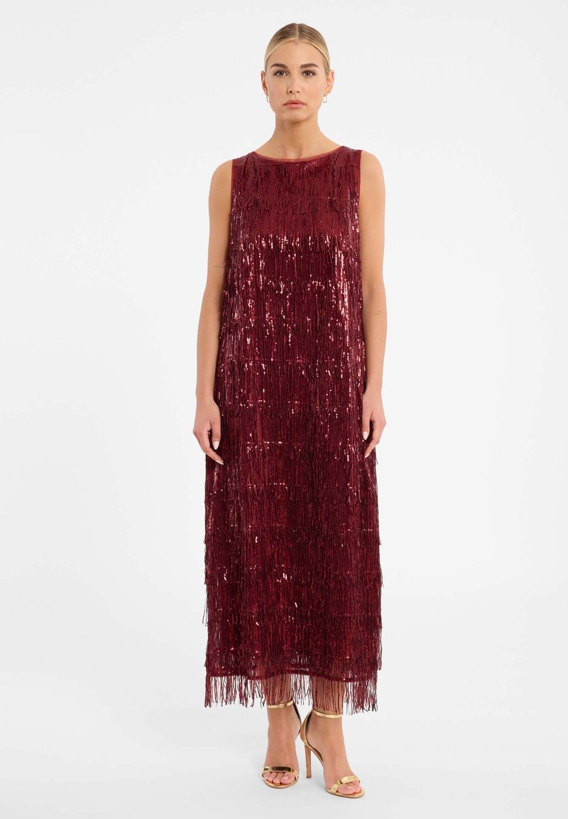 Bordeaux mouwloze jurk met franjes en pailletten, met een rechte silhouet. Gemaakt in combinatie met gouden sleehakken.