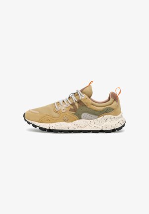 Hoge sneaker in tan en olijfgroen met een witte zolen met spikkels, witte veters en oranje aantreklussen, ontworpen voor casual buitengebruik.