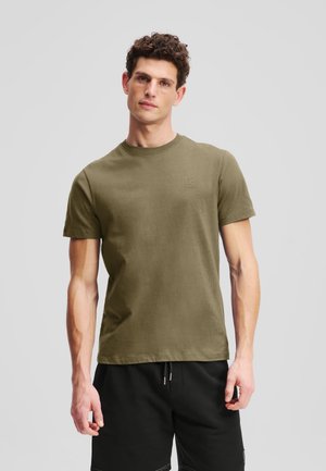 Olijfgroene katoenen t-shirt met korte mouwen en ronde hals. Heeft een subtiele logodetail op de borst, een gladde textuur en een fitted vorm.