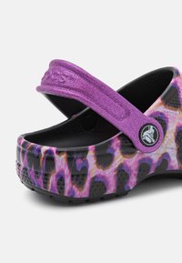 Purple and black clog with a leopard print pattern, featuring a textured strap and a round logo accent in black.