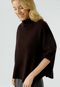 Dunkelbrauner Oversize-Pullover mit hohem Kragen, weichem Material und lockeren Ärmeln. Verfügt über einen geraden Saum und minimale Nähte.