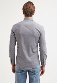 Camicia a maniche lunghe con motivo a quadri, dotata di colletto, polsini abbottonati e orlo curvo, realizzata in un tessuto leggero in tonalità scure.