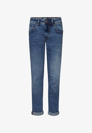 Czarna koszulka z krótkim rękawem z okrągłym logo na piersi, w połączeniu z niebieskimi dżinsami i białymi sneakersami z czarnymi akcentami.