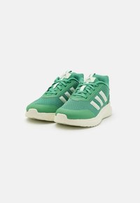 Chaussures de sport vertes en maille et matériaux synthétiques, avec des rayures et accents blancs, dotées d'une semelle texturée pour une meilleure adhérence.