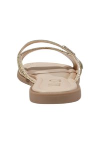 Sandal in metallo dorato con cinturini, presenta una suola piatta beige e una soletta liscia, mettendo in mostra due cinturini sottili con una leggera lucentezza.