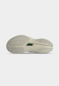 Λαστιχένια σόλα παπουτσιού Saucony με υφή προφίλ που περιλαμβάνει γραμμές και κυκλικά σχέδια, εμφανιζόμενη σε απλό λευκό φόντο.