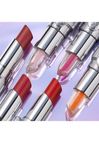 Five lipsticks with chrome casings. Shades include deep red, pink, and orange, alongside a clear one with shimmer. Smooth texture.