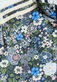 Látka s kvetinovým vzorom, ktorá zobrazuje rôzne kvety v modrej, ružovej a bielej farbe na tmavom pozadí; hladká textúra a jemný povrch.