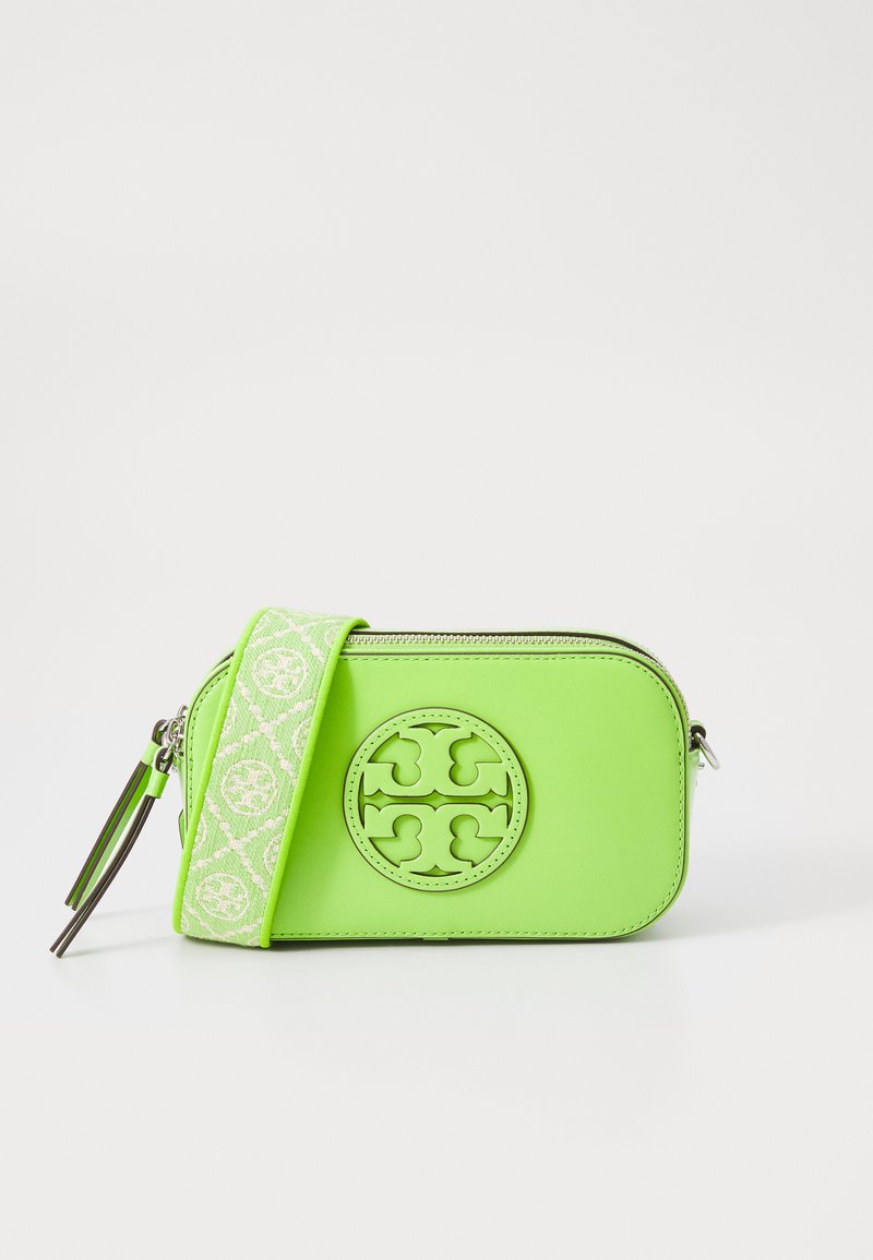 Bolso cruzado de piel verde con un medallón de logo, cierre de cremallera y una correa con patrón. Presenta herrajes plateados y textura suave.