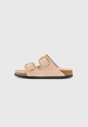 Infradito rosa con due fibbie dorate, suola in sughero e suola in gomma nera. Materiale liscio con design piatto e open-toe.