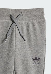 Pantaloni da tuta in cotone grigio con vita regolabile, caratterizzati da una leggera trama melange e un logo Adidas ricamato di un grigio scuro sulla gamba sinistra.