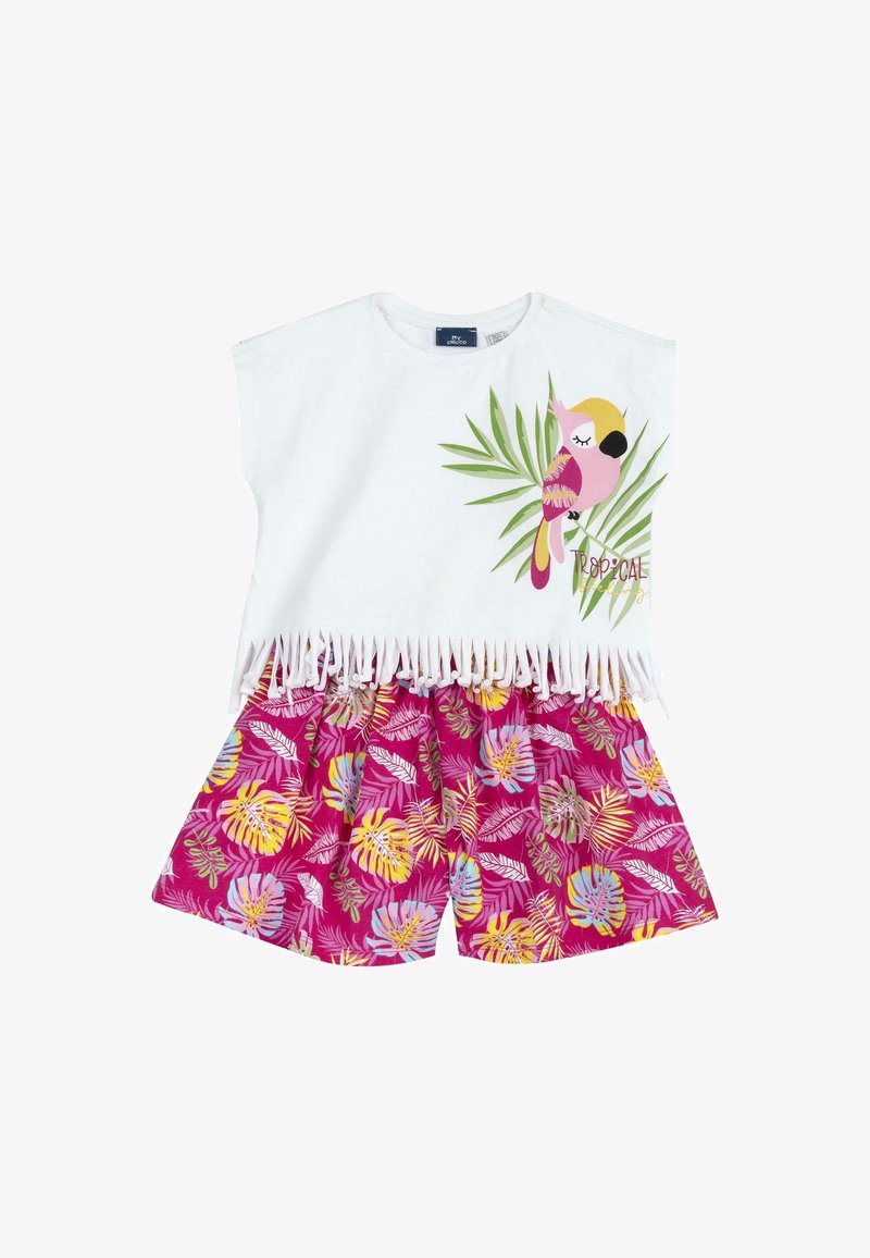 Top in cotone bianco con frange e stampa di pappagallo tropicale, abbinato a pantaloni corti rosa con motivi di foglie colorate.