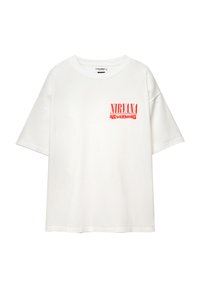T-shirt en coton blanc à manches courtes, avec le texte rouge "NIRVANA" et "NEVERMIND" sur la poitrine gauche. Coupe relaxée et encolure ronde.