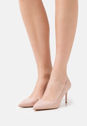 Talons hauts en suede rose pâle avec un bout pointu et un talon stiletto mince, arborant une texture lisse et un design minimaliste.