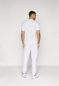 Weißes Baumwoll-T-Shirt und passende Sweatpants. Das Outfit zeichnet sich durch einen lockeren Schnitt, einen runden Ausschnitt und dezente Stickdetails aus.