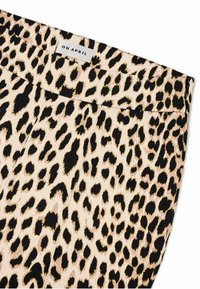 Leopardmønster stoff med en beige og svart fargepalett. Har en glatt tekstur og en rett midje med etikett som sier "OH APRIL."