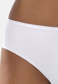 Close-up of a person wearing white seamless underwear, showing the fabric texture and fit around the hip area.