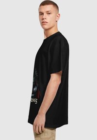 Sort grafisk t-shirt med et stort design af en krigerkarakter, korte ærmer, rund halsudskæring og en løs pasform.