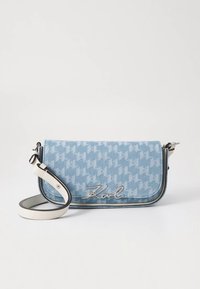 Blaue Denim-Umhängetasche mit Hahnentrittmuster, silbernem Logo, weißem Riemen und schwarzer Einfassung. Verfügt über einen Klappenverschluss. Kompaktes und strukturiertes Design.