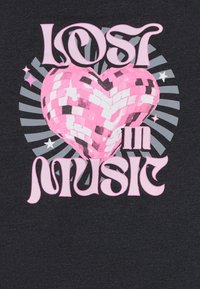 Schwarzes T-Shirt mit einer rosa herzförmigen Discokugel und dem Text "VERLOREN IN MUSIK" in fetten rosa Buchstaben, vor grauen radialen Linien.