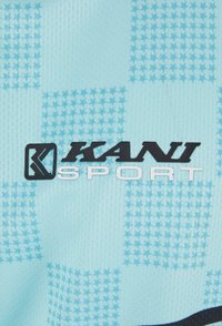 Gaiši zils sporta audums ar teksturētu zvaigžņu rakstu. Iekļauts melnais "KANI" logo un "SPORT" baltā krāsā. Gluda, sportiska forma.