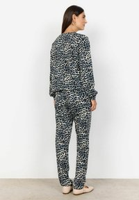 Ensemble de loungewear imprimé léopard dans des nuances de bleu et de crème, avec une coupe décontractée, des manches longues et un pantalon à taille élastique. Texture de tissu lisse.