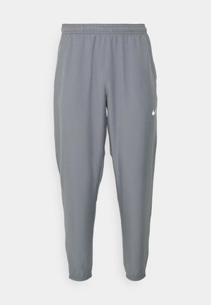Pantaloni sportivi grigi con vita elastica e polsini. Presentano un logo Nike bianco sul lato sinistro. Realizzati in un tessuto leggero.