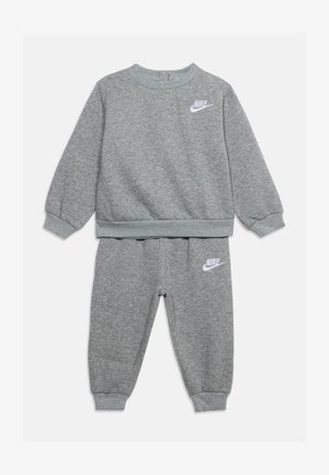 Dziecięcy dwuczęściowy szary dres Nike z długimi rękawami, elastycznymi mankietami i białymi logotypami Nike na piersi i lewym udzie.