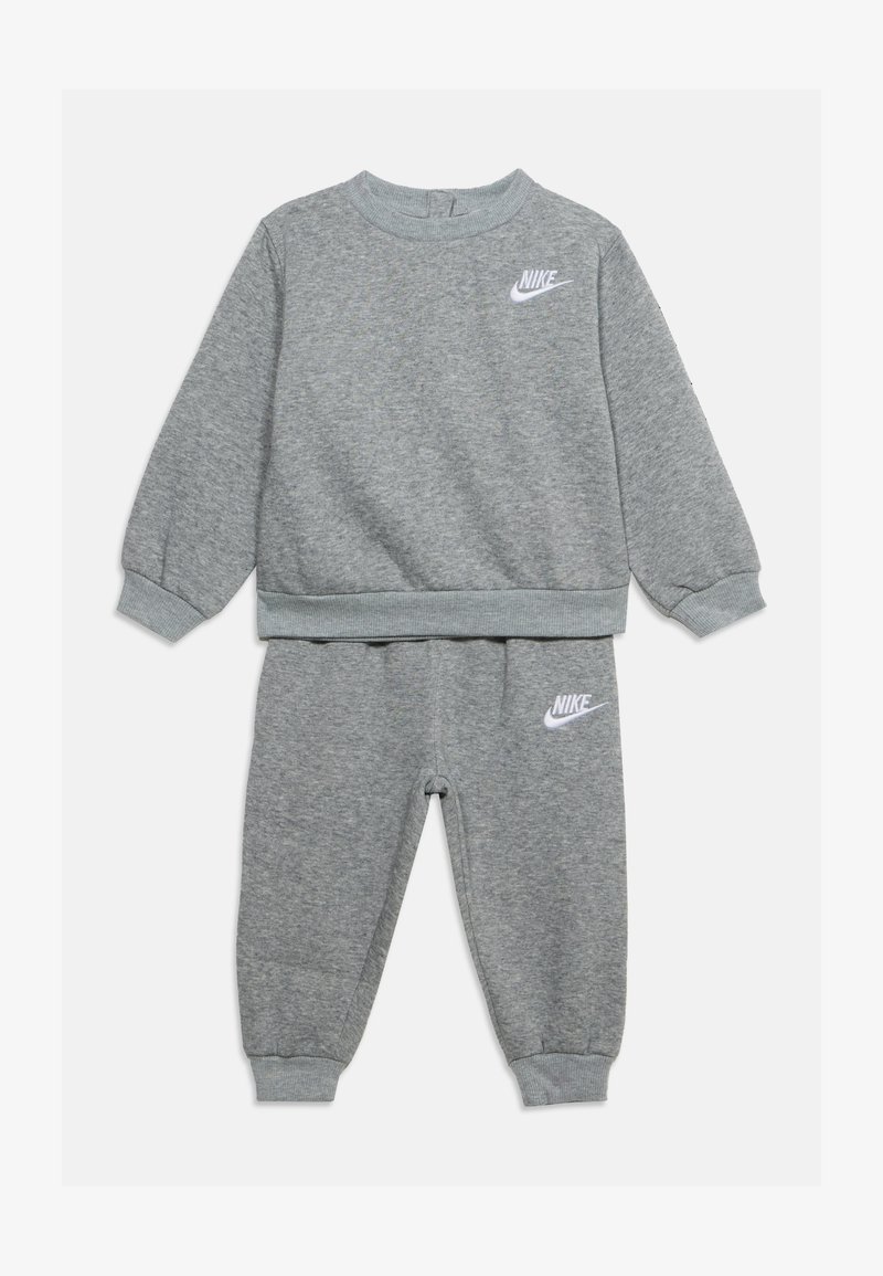 Παιδικό γκρι σετ φόρμας Nike δύο τεμαχίων με μακριά μανίκια, ελαστικά μανσέτες και λευκά λογότυπα Nike στο στήθος και στον αριστερό μηρό.