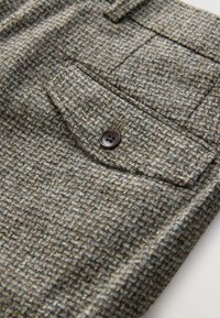 Twill fabric trousers in gray and brown tones, featuring a textured pattern and a brown button on a front pocket.