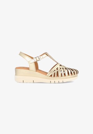 Sandalia cuña de oro y beige con punta abierta, correa y diseño troquelado que presenta acentos metálicos. Parte superior sintética ligera y texturizada. Suela de goma.