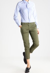 Ljusblå skjorta med lång ärm, i kombination med olivgröna korta byxor och svarta loafers. Slät tyg, skräddarsydd passform.