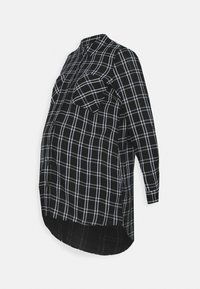 Svart och vit rutig gravidskjorta, med långa ärmar, knäppning framtill, två bröstfickor, svängd fåll och mjuk tygtextur.