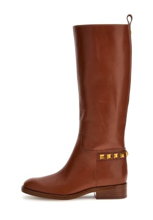 Botte en cuir marron haute jusqu'au genou avec un petit talon empilé et des clous carrés dorés près de la cheville du côté extérieur.