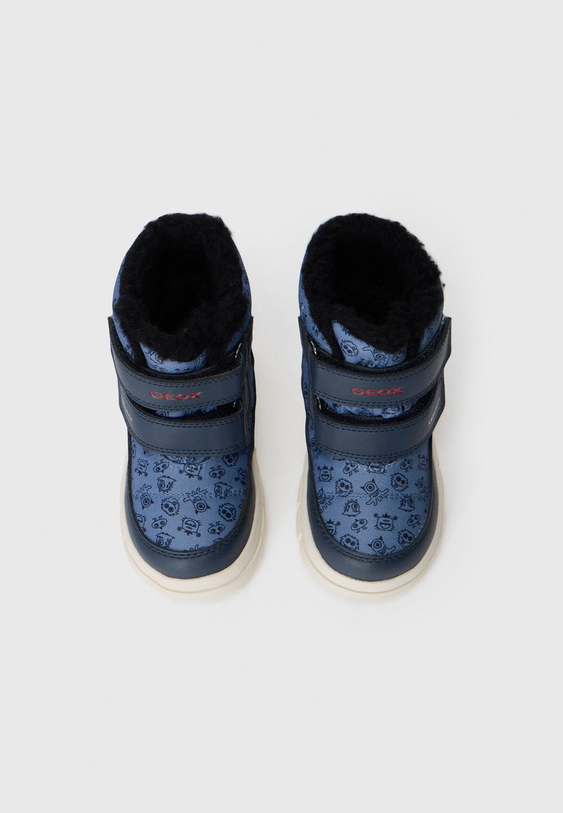 Niebieskie buty Geox z futrzanym czarnym wykończeniem, posiadające wzorzystą cholewkę i dwa regulowane paski na rzepy. Jasna gumowa podeszwa.