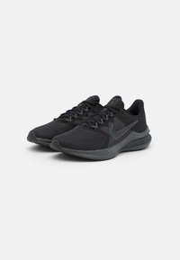 Zapatos deportivos negros con parte superior de malla, acentos texturizados, collar acolchado y suela de goma con un diseño aerodinámico.