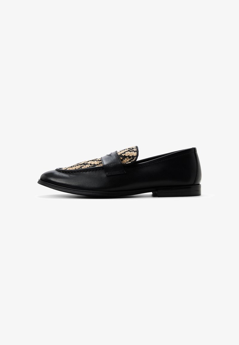 Mocasín de cuero negro con panel y detalle de correa de tela tejida en color beige, suela plana y punta redondeada, visto de lado sobre fondo blanco.