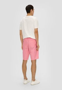 Lichte roze shorts met een elastische tailleband en achterzakken, gecombineerd met een eenvoudig wit t-shirt met korte mouwen en een ontspannen pasvorm.