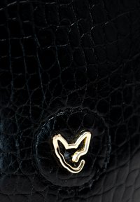 Borsa nera in pelle con finitura goffrata effetto coccodrillo, dotata di un accento circolare in tonalità oro a forma di faccia di animale.