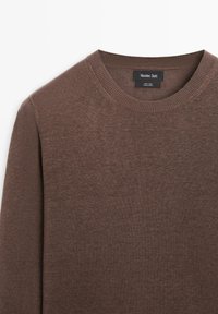 Pull marron à col rond et manches longues en lin 100 % avec une étiquette de marque Massimo Dutti visible à l'intérieur du col.