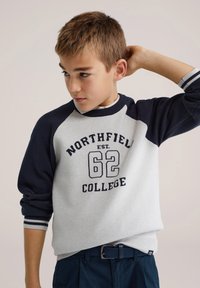 Sweat-shirt gris et marine à manches raglan, avec l'inscription "NORTHFIELD COLLEGE 62" imprimée en marine. Poignets et ourlet côtelés. Texture en maille plate.