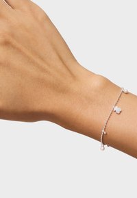 Bracciale in argento con un charm a forma di farfalla, piccole perle e dettagli in perline. La catena è delicata con una consistenza fine e un design semplice.