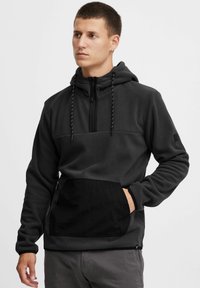 Donkergrijze fleece hoodie met een zwarte nylon voorzak, halve rits sluiting, verstelbare koordkap, en elastische manchetten.